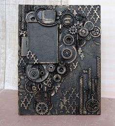 an altered photo frame with gears and wheels on it's side, sitting on top of a table