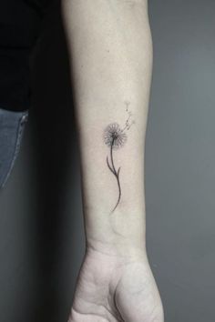 a small dandelion tattoo on the left inner arm and wrist, done in black ink