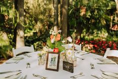 the table is set with flowers in vases and place settings for guests to sit at