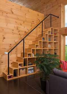 a living room filled with furniture next to a wooden wall covered in bookshelves