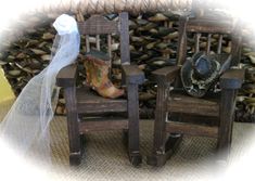 two wooden chairs sitting next to each other in front of a pile of firewood