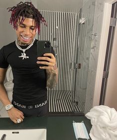 a man with dreadlocks taking a selfie in the bathroom