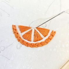 an orange slice is stitched on to a piece of fabric