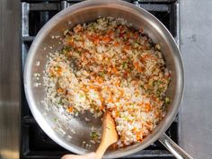 rice and carrots being cooked in a pan on the stove