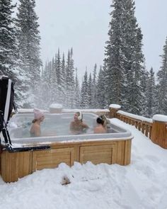 three people in a hot tub surrounded by snow