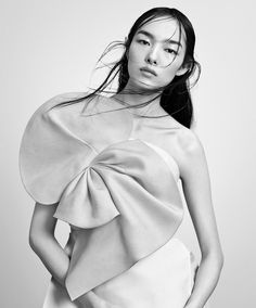 a black and white photo of a woman in a dress with her hair blowing in the wind