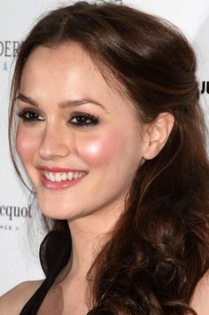 a close up of a person with long hair smiling at the camera and wearing a black dress