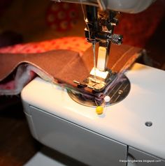 the sewing machine is on top of the white piece of fabric that has been sewn