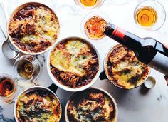 an overhead view of several dishes of food and drinks on a marble table with wine glasses