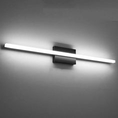 a bathroom light that is lit up on the wall in black and white photo with dim lighting