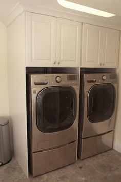 the washer and dryer are next to each other in this laundry room with white cabinets