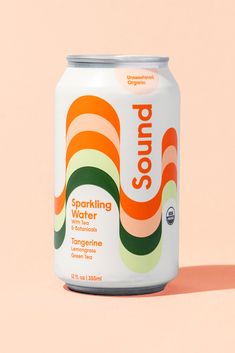 a can of sparkling water sitting on top of a pink surface with an orange and green stripe