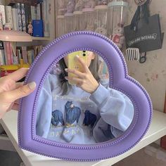 a woman taking a selfie in a purple heart shaped frame with her cell phone