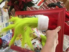 a person is holding up a christmas elf's hat in front of a red frame