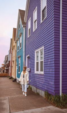 a woman is walking down the sidewalk in front of some colorful houses