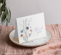 a thank you card sitting on top of a plate next to a potted plant