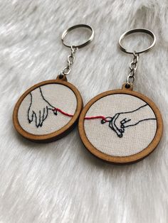 two wooden hoops with embroidered images of hands holding each other's hand on them