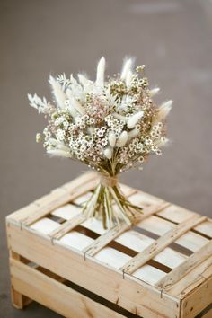 a bouquet of white flowers sitting on top of a wooden pallet with no one around it