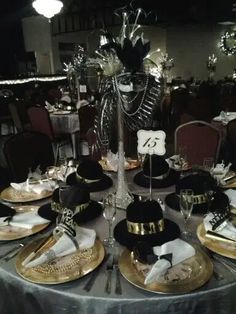 the table is set with black and gold plates, silver napkins, and hats