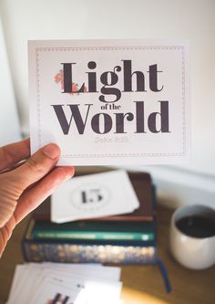 a person holding up a card with the words light of the world written on it