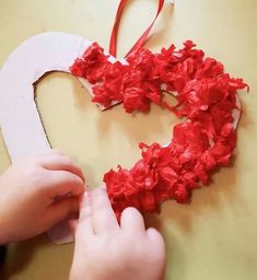 a child is making a heart out of tissue paper