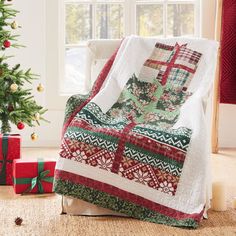 a living room with a christmas tree, presents and a quilted blanket on the couch