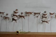 a group of metal animals hanging on a wall next to a vase with flowers in it