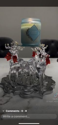 a glass candle holder sitting on top of a table next to a reindeer figurine