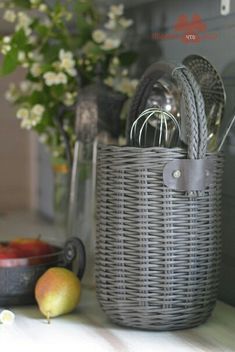 a gray basket sitting on top of a table next to some fruit and utensils