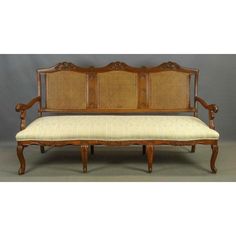 an antique wooden bench with cane back and upholstered seat padding, on grey background