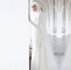 a woman in a white wedding dress standing next to a wall with columns and arches