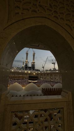 the view through an archway into a large building with many people in it at dusk