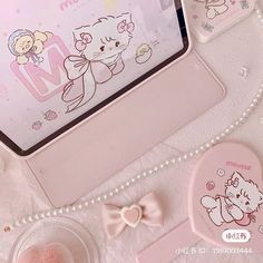 a pink tablet with hello kitty on the screen and other items around it, including a bow