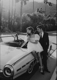 a man and woman standing next to a car