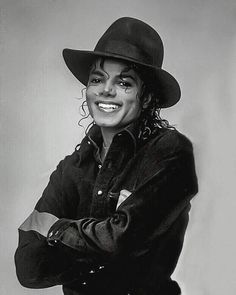 a black and white photo of a person wearing a hat with his arms crossed in front of him