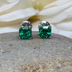 "The stud earrings pictured are lab created emerald #5519. Also shown in white gold. Earring back style is subject to change due to availability. -Approximate total carat weight: 2.00ctw. -Center Stone Size: 6x6mm - approx. 1.00ct each diamond equivalent -Center Stone Shape: Asscher cut -Gem Type: lab created emerald -Stone Clarity: VS2 -Stone Color: lively medium green, eye-clean -Moh's Scale: 8.5 hardness -Metal Type and Purity: 14k yellow gold -Setting: 4 prong basket head -Backing: friction Classic Emerald Earrings For Anniversary, Classic May Birthstone Earrings As Gift, Classic Earrings For May Birthstone Gift, Classic Earrings As Gift For May Birthstone, Classic Emerald Earrings For May Birthstone, May Birthstone Earrings For Anniversary, Classic Green Earrings For Anniversary, Emerald Cut Earrings With Prong Setting As Gift, Emerald Cut Earrings With Prong Setting