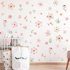 a baby's room with pink flowers on the wall and a white crib