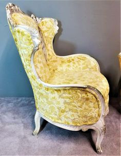 an old yellow chair sitting in front of a blue wall