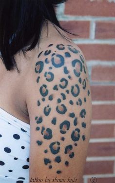 a woman with a tattoo on her arm has a leopard print design on it's shoulder