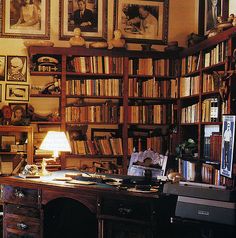 an office with many bookshelves and pictures on the wall, including a desk