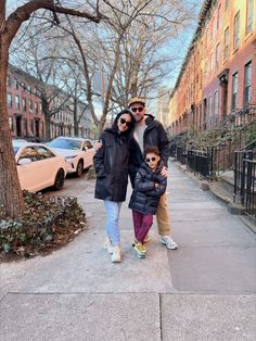 a man, woman and child are standing on the sidewalk