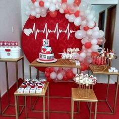 a table topped with cake and cupcakes next to a heart shaped balloon wall