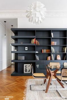 a dining room table and chairs in front of a bookshelf