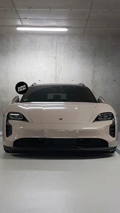 a white sports car parked in a parking garage next to a black and white sign