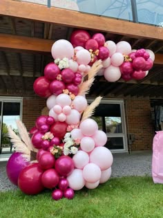 a large balloon letter made out of balloons and flowers in front of a brick building