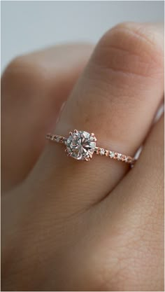 a woman's hand with a diamond ring on top of her finger and an engagement band