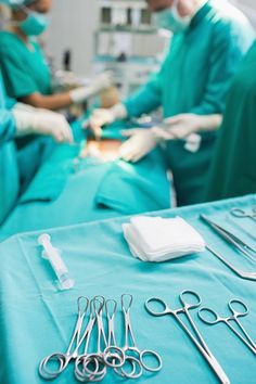 surgical instruments are sitting on a table in an operating room as two surgeons look on