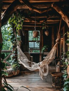 a hammock hanging from the ceiling in a room filled with greenery and potted plants