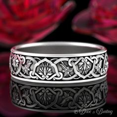 an intricately designed wedding band with flowers in the background