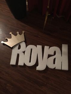 the word royal with a crown cut out of it on top of a wooden floor